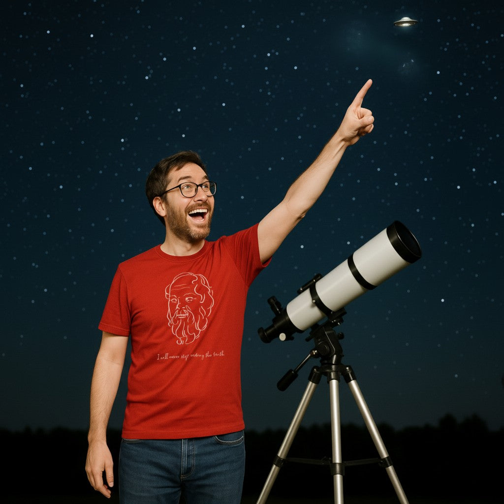 Excited man pointing his finger at small flying object in the night sky. He is wearing a red t-shirt with a white graphic of Socrates's head, the quote 'I will never stop seeking the truth' and the blue text 'Socrates 399 BC' below.