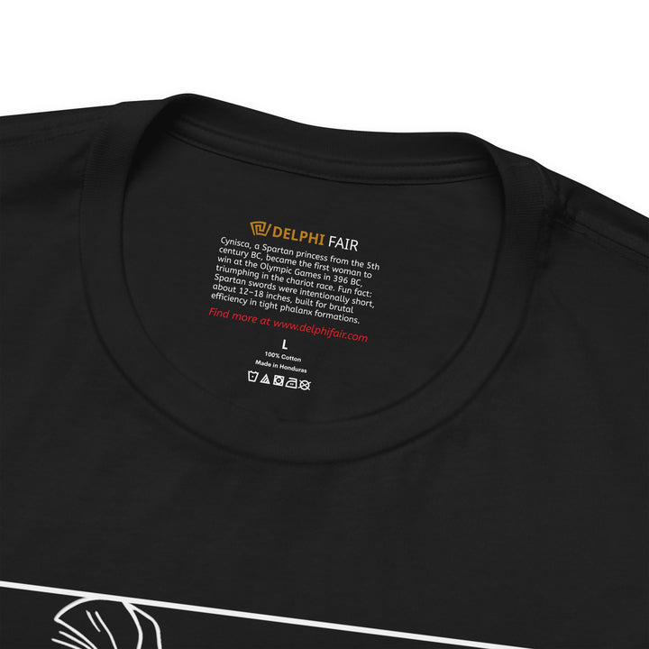 Close-up of a black t-shirt neck label with the text about Cynisca, the first female Olympic victor, and a fun fact about Spartan swords being short and designed for close combat in phalanx formations.