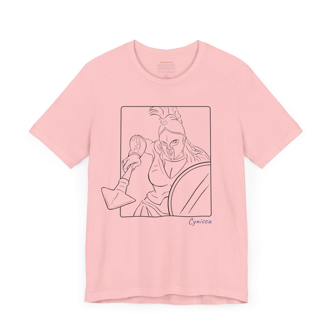 Pink t-shirt with a black line graphic of Cynisca in a dynamic close-up pose, wearing a helmet and holding spear and shield inside a rectangular frame, with the blue text 'Cynisca' below the design.