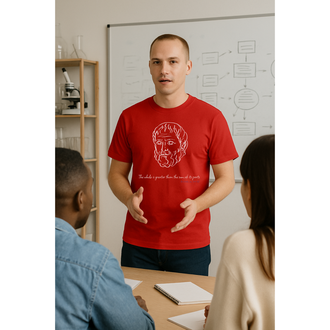 Man explaining something at the meeting. He is wearing a red t-shirt with a white graphic of Aristotle's head, the quote 'The whole is greater than the sum of its parts' and the blue text 'Aristotle ca. 340 BC' below