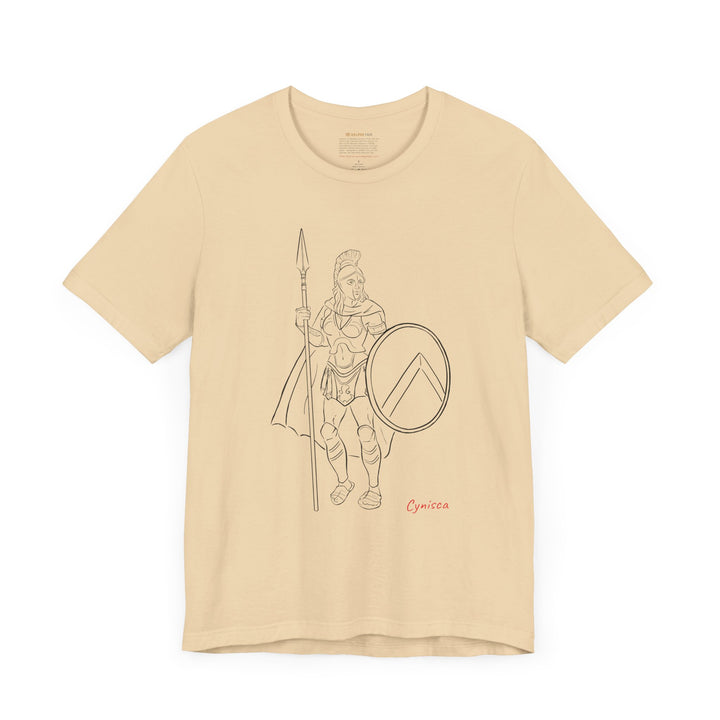 Soft-cream t-shirt with a black line graphic of Cynisca standing in full Spartan armor, holding a spear and a round shield with a lambda symbol, with the red text 'Cynisca' below the design.