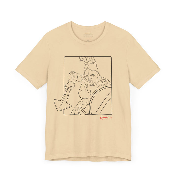 Soft-cream t-shirt with a black line graphic of Cynisca in a dynamic close-up pose, wearing a helmet and holding spear and shield inside a rectangular frame, with the red text 'Cynisca' below the design.