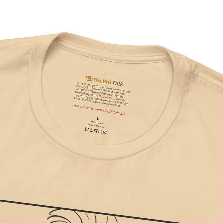 Close-up of a soft-cream t-shirt neck label with the text about Cynisca, Olympic champion from ancient Sparta, and a fun fact about Spartan spears measuring up to 7–9 feet long.