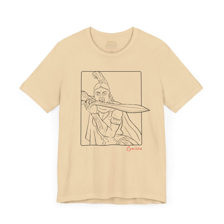 Soft-cream t-shirt with a black line graphic of Cynisca in a dramatic close-up pose, holding a sword across her chest inside a rectangular frame, with the red text 'Cynisca' below the design.